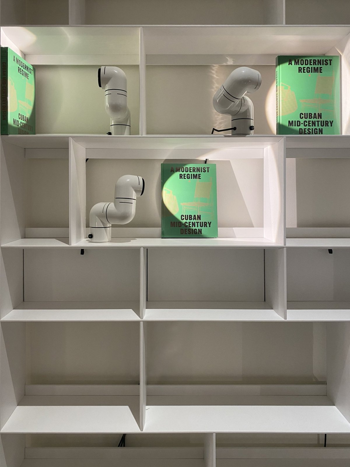 El libro Un régimen modernista. Diseño cubano de mediados del Siglo XX en el showroom de MINIM Madrid acompañado de las lámparas TATU de Santa&Cole